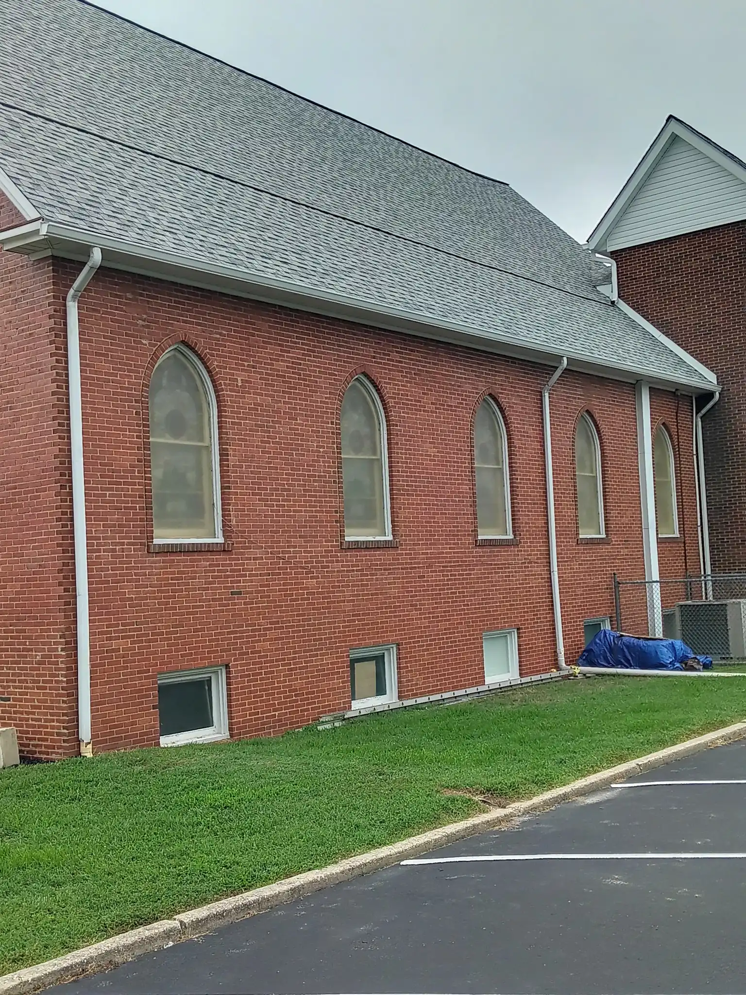 Brick church exterior featuring arched windows, a sloped roof, and well-maintained grass. Relevant for discussions on architectural design or community buildings.